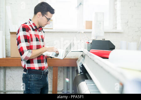 Man with laptop working in printing office Stock Photo