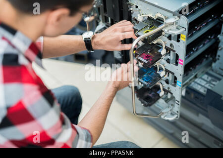 Crop man setting colorful inks in printer Stock Photo