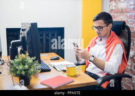 Young designer using phone in office Stock Photo
