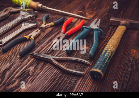 Different Working tools on a wooden table - a hammer, wire cutters, pliers, chisels and wrenches Stock Photo