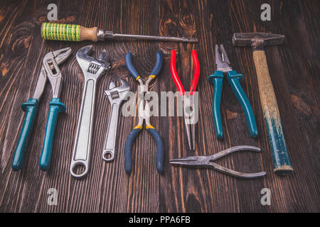 Different Working tools on a wooden table - a hammer, wire cutters, pliers, chisels and wrenches Stock Photo