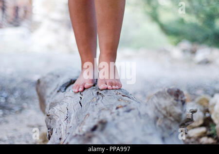 Hippies girl standing cross legged on a large stump Stock Photo