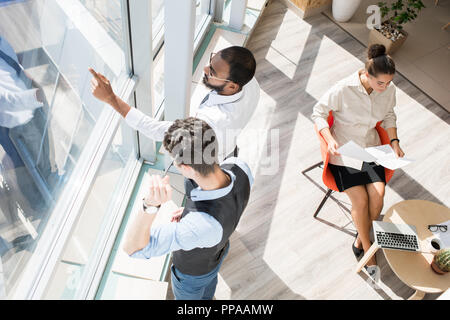 Above view portrait of young business people working in sunlit modern office with big windows Stock Photo