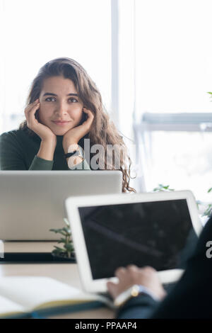 Portrait of young Latin-American woman smiling at camera while working with laptop in open space office Stock Photo