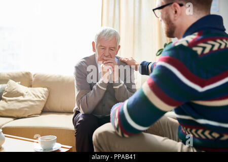 Back view portrait of male psychologist consoling depressed senior man during therapy session, copy space Stock Photo