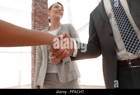 Businesspeople  shaking hands against room with large window loo Stock Photo