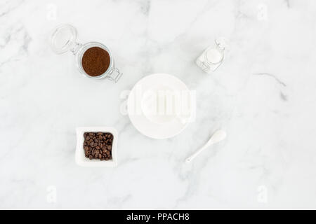 Concept with empty coffee cup, white sugar, ground coffee and coffee beans on white marble background. Stock Photo