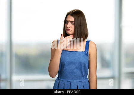 Young woman having sore throat. Unhappy girl suffering from pain in throat. Symptoms of flu. Stock Photo