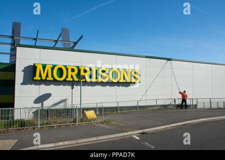Westgate Retail and Leisure Park - exterior of Morrisons supermarket with man cleaning the outside wall with long pole squeegee, Aldershot, UK Stock Photo