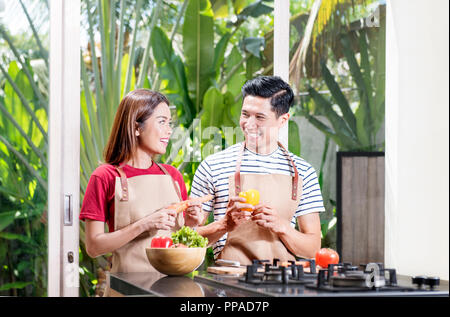 Happy asian couple preparing fresh vegetables for cooking on kitchen Stock Photo