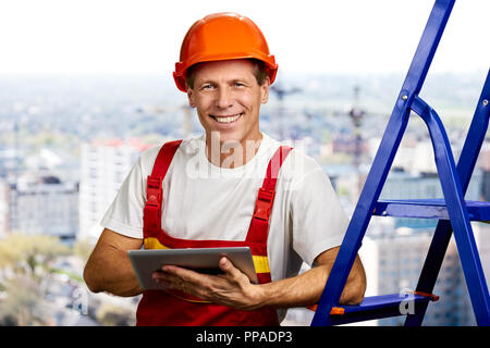 Smiling builder working on computer tablet. Stock Photo