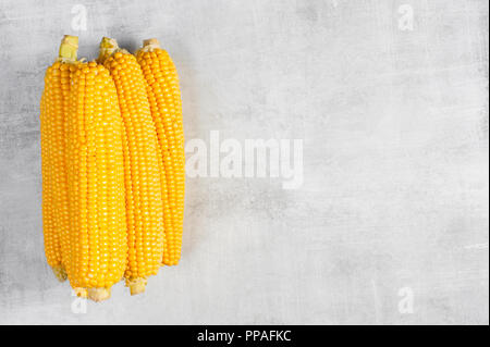 Pilled fresh corn cobs on the textured grey table, top view Stock Photo