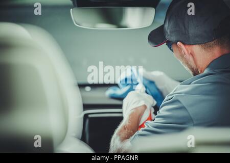 Modern Car Interior Cleaning and Detailing by Professional Caucasian Cleaner. Stock Photo