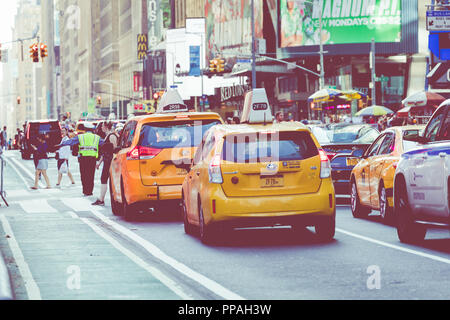 NEW YORK - SEPTEMBER 2, 2018: Yellow cab speeds through Times Square the busy tourist intersection of neon art and commerce and is an iconic street of Stock Photo