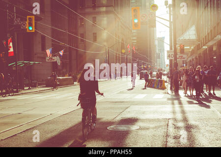 TORONTO, CANADA - SEPTEMBER 17, 2018: Rush hour at Toronto downtown, many people on the street. Sunset time with sun flares. Stock Photo