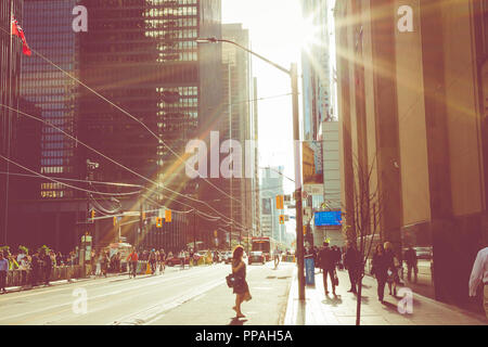 TORONTO, CANADA - SEPTEMBER 17, 2018: Rush hour at Toronto downtown, many people on the street. Sunset time with sun flares. Stock Photo