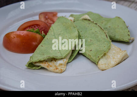 delicious quesadillas with green tortilla with panela cheese and tomato on a white plate Stock Photo