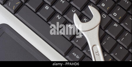 Spanner on the laptop keyboard, the concept of repairing machinery, close-up Stock Photo