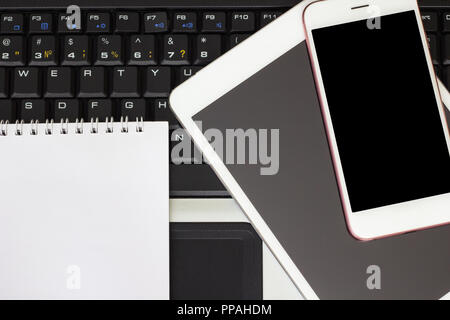 Notepad, smartphone and tablet on the laptop keyboard, business concept Stock Photo
