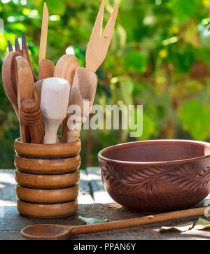 empty clay plate and various wooden kitchen objects in a container on a table Stock Photo