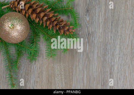A white pine cone and a gold ornament on spruce boughs with copy space Stock Photo
