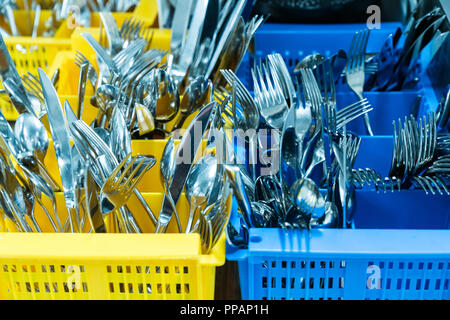 silverware and cutlery in colorful palstic ocntainer in an industrial restaurant kitchen clean and fresh out of the dishwasher Stock Photo