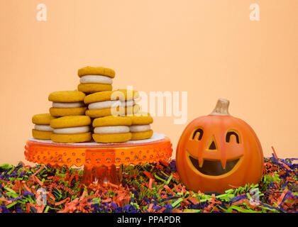 Naturally  flavored Pumpkin Spice cookies with cinnamon cream cheese filling on an orange pedestal with pumpkin jack-o-lantern black orange and green  Stock Photo