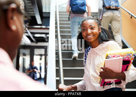 Female High School Student Talking With Teacher In Busy Corridor Stock Photo
