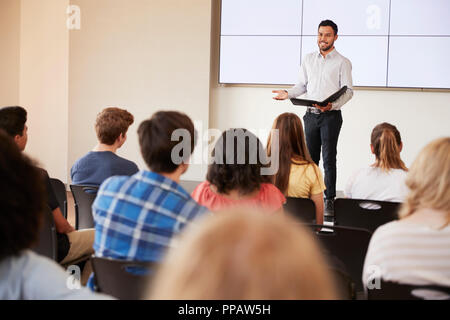 Teacher Giving Presentation To High School Class In Front Of Screen Stock Photo