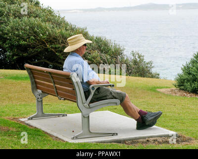 SENIOR CITIZEN sitting on bench enjoying the view Stock Photo