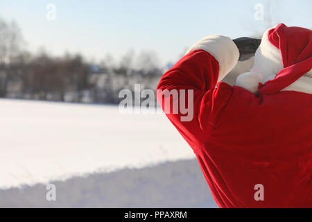 Santa Claus comes with gifts from the outside. Santa in a red su Stock Photo