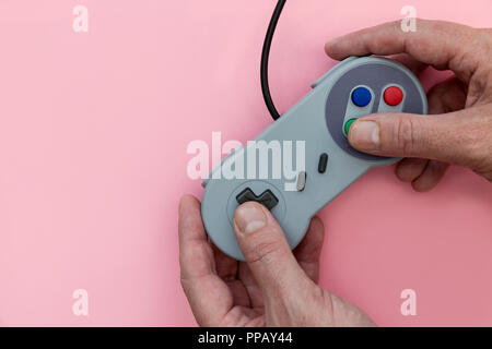 Man playing video game with controller on pink background Stock Photo