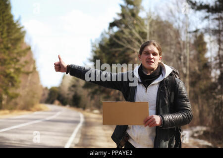 A young man is hitchhiking around the country. The man is trying Stock Photo