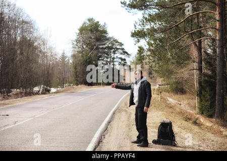 A young man is hitchhiking around the country. The man is trying Stock Photo