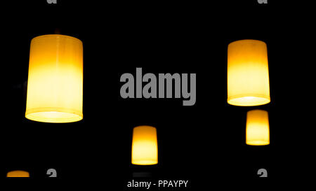 Nice hanging tube shaped decorative ceiling light on a very dark room. Stock Photo