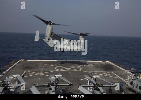 MINDANAO SEA– U.S. Marines in a MV-22B Osprey with Marine Medium Tiltrotor Squadron 166 Reinforced, 13th Marine Expeditionary Unit (MEU), fly off of the San Antonio-class amphibious transport dock USS Anchorage (LPD 23) during a regularly scheduled deployment of the Essex Amphibious Ready Group (ARG) and 13th MEU, August 17, 2018. The Essex ARG/13th MEU is a capable and lethal Navy-Marine Corps team deployed to the 7th Fleet area of operations to support regional stability, reassure partners and allies and maintain a presence postured to respond to any crisis ranging from humanitarian assistan Stock Photo
