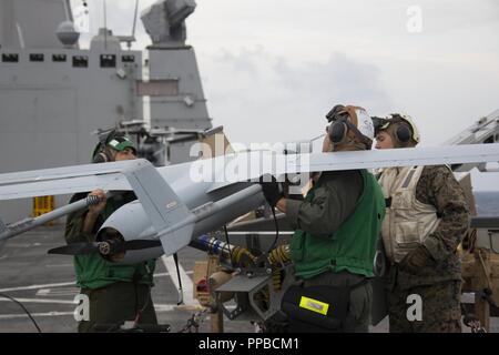 MINDANAO SEA – U.S. Marines with Unmanned Vehicle Squadron 1, Marine Medium Tiltrotor Squadron 166 Reinforced, 13th Marine Expeditionary Unit (MEU), prepare an RQ-21A Blackjack for flight operations aboard the San Antonio-class amphibious transport dock USS Anchorage (LPD 23) during a regularly scheduled deployment of the Essex Amphibious Ready Group (ARG) and 13th MEU, August 17, 2018. The Essex ARG/13th MEU is a capable and lethal Navy-Marine Corps team deployed to the 7th fleet area of operations to support regional stability, reassure partners and allies and maintain a presence postured to Stock Photo