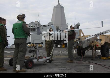 MINDANAO SEA – U.S. Marines with Unmanned Aerial Vehicle Squadron 1, Marine Medium Tiltrotor Squadron 166 Reinforced, 13th Marine Expeditionary Unit (MEU), prepare an RQ-21A Blackjack for flight operations aboard the San Antonio-class amphibious transport dock USS Anchorage (LPD 23) during a regularly scheduled deployment of the Essex Amphibious Ready Group (ARG) and 13th MEU, August 17, 2018. The Essex ARG/13th MEU is a capable and lethal Navy-Marine Corps team deployed to the 7th fleet area of operations to support regional stability, reassure partners and allies and maintain a presence post Stock Photo