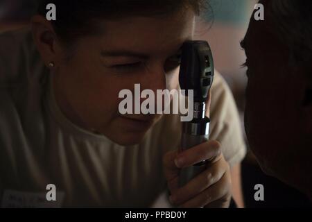 U.S. Air Force Maj. Lauren Matthews, 18th Medical Group optometrist, Kadena Air Base, Japan, examines a patient’s eye during Pacific Angel (PAC ANGEL) 18-4 in Vavuniya, Sri Lanka, Aug. 17, 2018. PAC ANGEL 18 is a joint and combined engagement that enhances participating nations’ humanitarian assistance and disaster relief capabilities while providing beneficial services to people in need throughout South and Southeast Asia and includes general health, dental, optometry, pediatrics and engineering programs as well as various subject-matter expert exchanges. Stock Photo