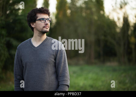 Calm man standing in the park looking to the left Stock Photo
