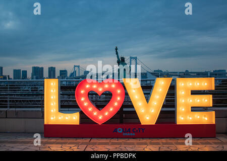 TOKYO, JAPAN - 21 FEB 2018: Love sign with lights, Japanese statue of liberty and rainbow bridge at blue hour Stock Photo