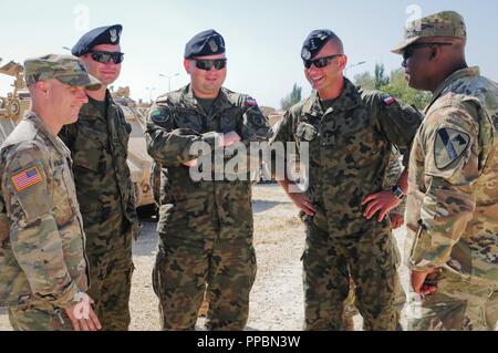 U.S. Army Lt. Col. Kelvin Swint, right,  the commander of 2nd Battalion, 5th Cavalry Regiment, 1st Armored Brigade Combat Team, 1st Cavalry Division and U.S. Army Capt. Ben Nygaard of Charlie Company, 2-5 Cav, 1st ABCT, 1st CD talk with Polish soldiers at the Mihail Kogalniceanu Air Base in Romania, Sept. 3, 2018. U.S. Army leaders of 2-5 Cav, 1st ABCT, 1st CD met with Polish soldiers to discuss future joint training opportunities in support of Atlantic Resolve, an enduring training exercise between NATO and U.S. forces. Stock Photo