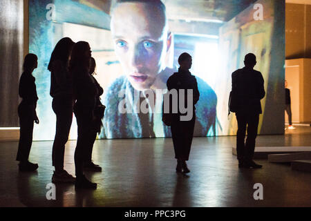 25 September 2018, Berlin: At the opening PK of the exhibition 'The Demon's Brain' by Agnieszka Polska, visitors watch a video installation. With film and animation, the Polish artist presents the fictional story of a rider who delivers documents. Historically based on the Polish salt mine manager Mikolaj Serafin from the 15th century, the installation is supposed to deal with the question of responsibility in today's time. The exhibition at the Hamburger Bahnhof - Museum für Gegenwart begins on 27.09.2018 and ends on 03.03.2019. Photo: Arne Immanuel Bänsch/dpa Stock Photo