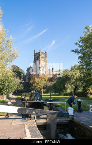 Kidderminster, UK. 25th September, 2018. UK weather: after an unseasonably cold evening and chilly start, the folk of Kidderminster welcome this morning's glorious autumn sunshine which is set to last for the remainder of the day. A British couple can be seen here enjoying their UK staycation, on a boating holiday navigating a canal narrow boat through the Kidderminster lock by St. Mary's Church. Credit: Lee Hudson/Alamy Live News Stock Photo