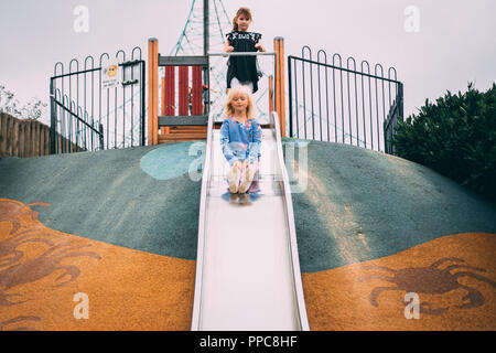 blonde girl play on slide in play park Stock Photo