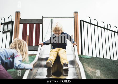 small boy on slide in play park Stock Photo