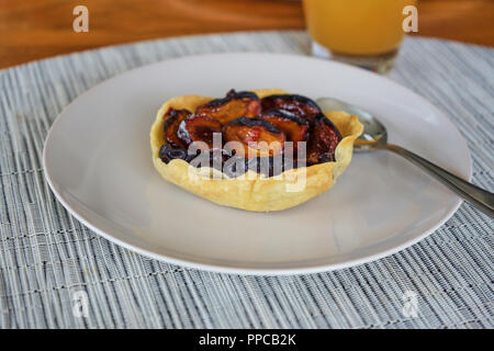 Plum Pie Right Out The Oven On A Withe Plate On A Wooden Table With An Apple Juice Glass Stock Photo