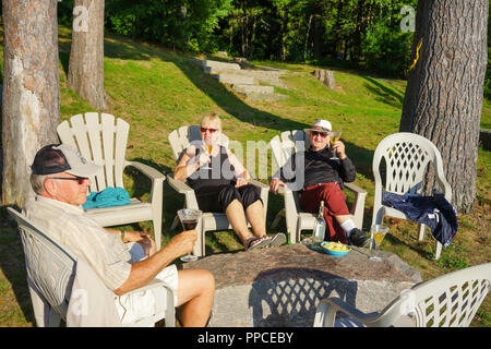 Lake of Bays near Dwight , Ontario, Canada, people relaxing with a drink on the sandy beach Stock Photo