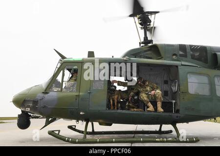 Members of the 5th Security Forces Squadron military working dog section prepare to take off with the 54th Helicopter Squadron during flight familiarization training at Minot Air Force Base, North Dakota, Aug. 23, 2018. This was the first time the K-9 unit has flown with the 54th Helicopter Squadron. Stock Photo