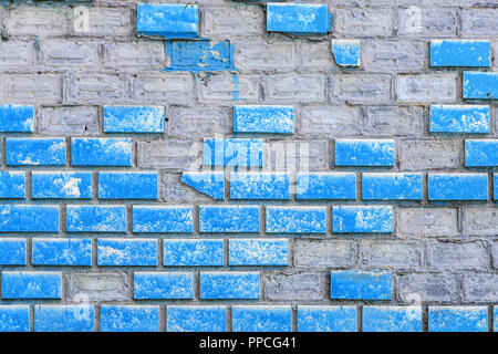 Old weathered blue painted brick wall with elements missing. Aged block surface with parts fall off. Concrete grunge outdor urban background Stock Photo